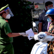 Un policier rend le permis de voyage à un banlieusard après avoir vérifié à
un poste de contrôle de rue à Vung Tau, au Vietnam, le lundi 6 septembre 2021.